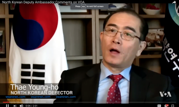 Man in suit with Korean flag behind him