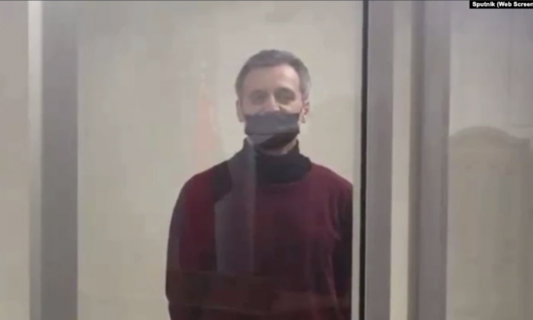man behind glass wearing a mask