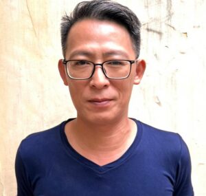 Asian man wearing glasses and a blue t-shirt