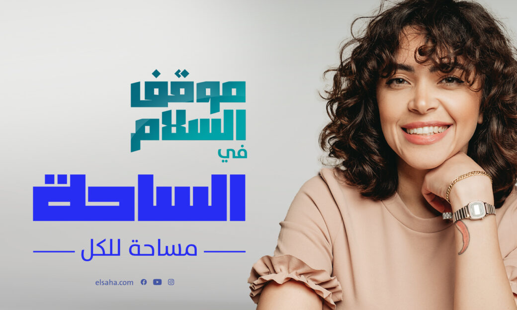 Woman with brown short curly hair smiling in a t-shirt next to Arabic-language text